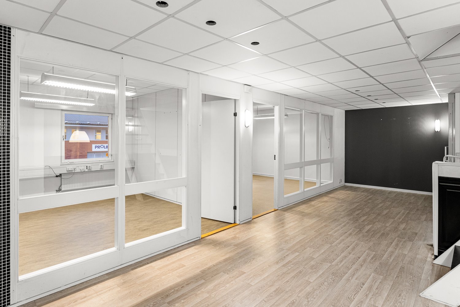 Ljust och effektivt planerat kontorsavsnitt med glaspartier som ger både transparens och avskildhet.