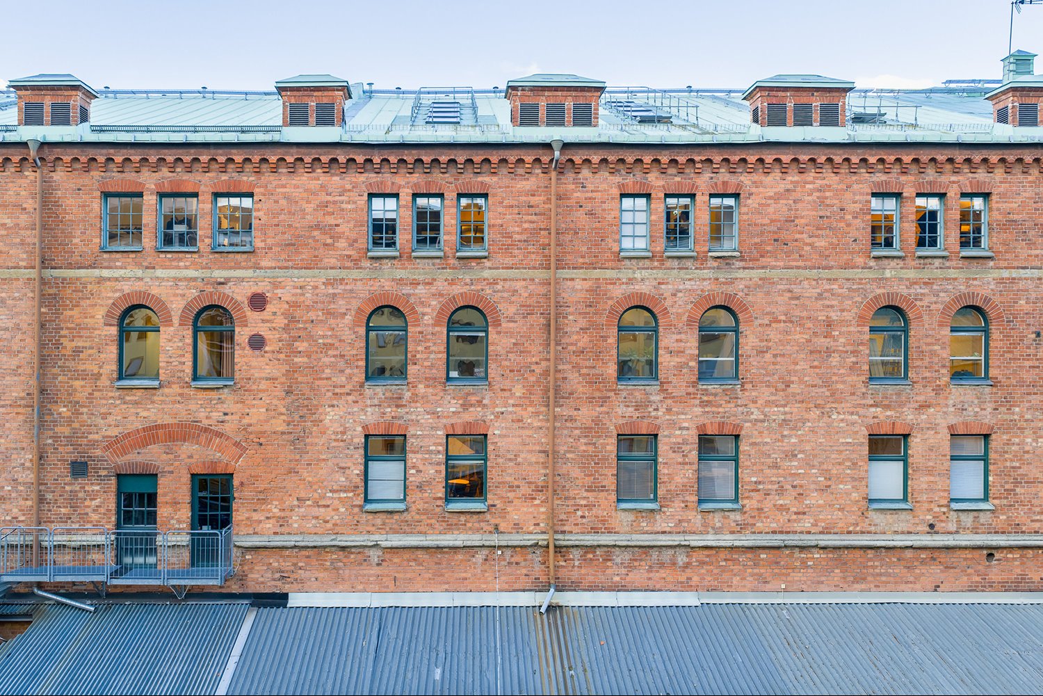 Klassisk fasad med välvda fönster och gröna detaljer – en byggnad med historia och själ.