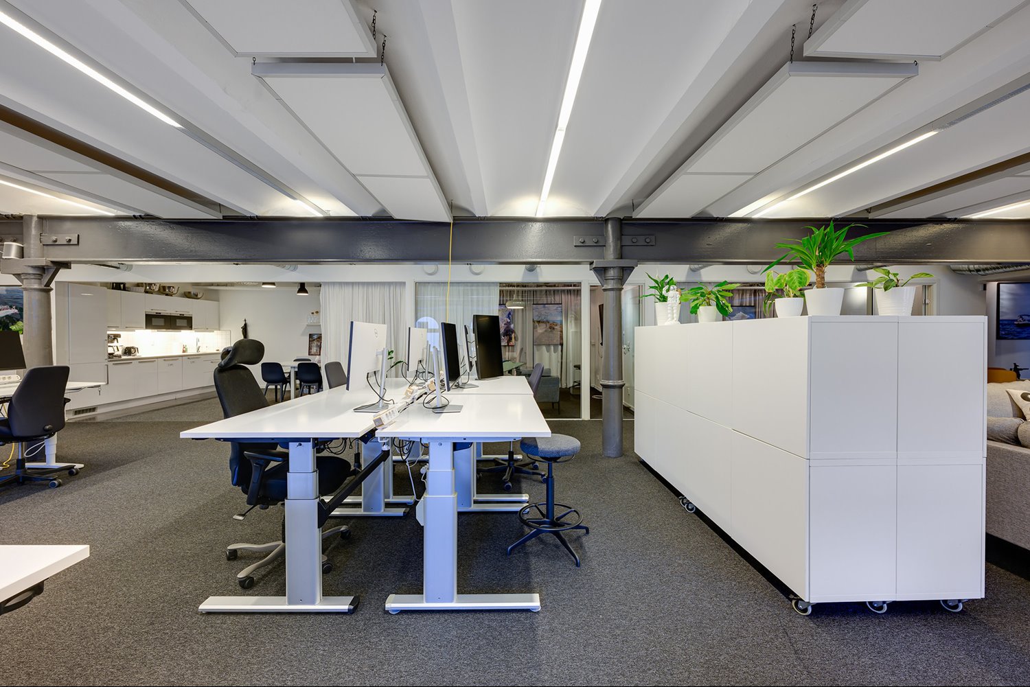 Moderna höj- och sänkbara skrivbord och genomtänkt belysning för en effektiv arbetsdag.