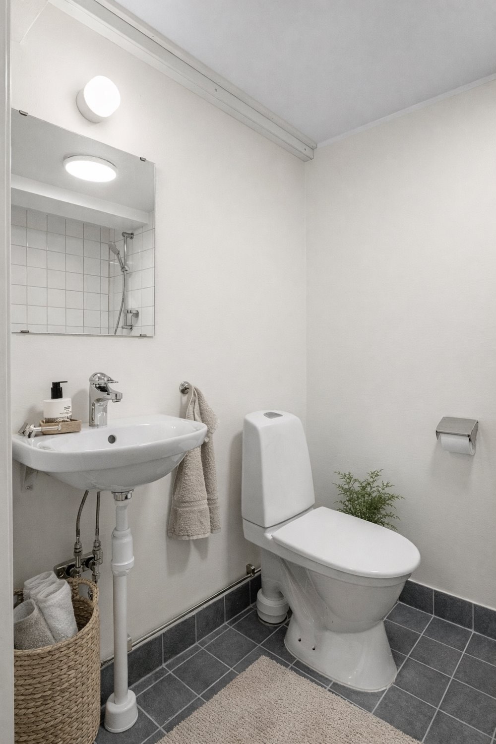 Fräscht WC-utrymme med handfat, spegel och god belysning. En enkel och funktionell personaldel som kompletterar lager- och kontorsytorna.