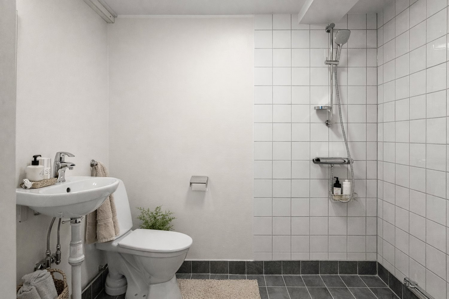 Fullt utrustat badrum med både WC och dusch i ett funktionellt och lättskött utförande. En praktisk lösning för personalens komfort i lokalen.