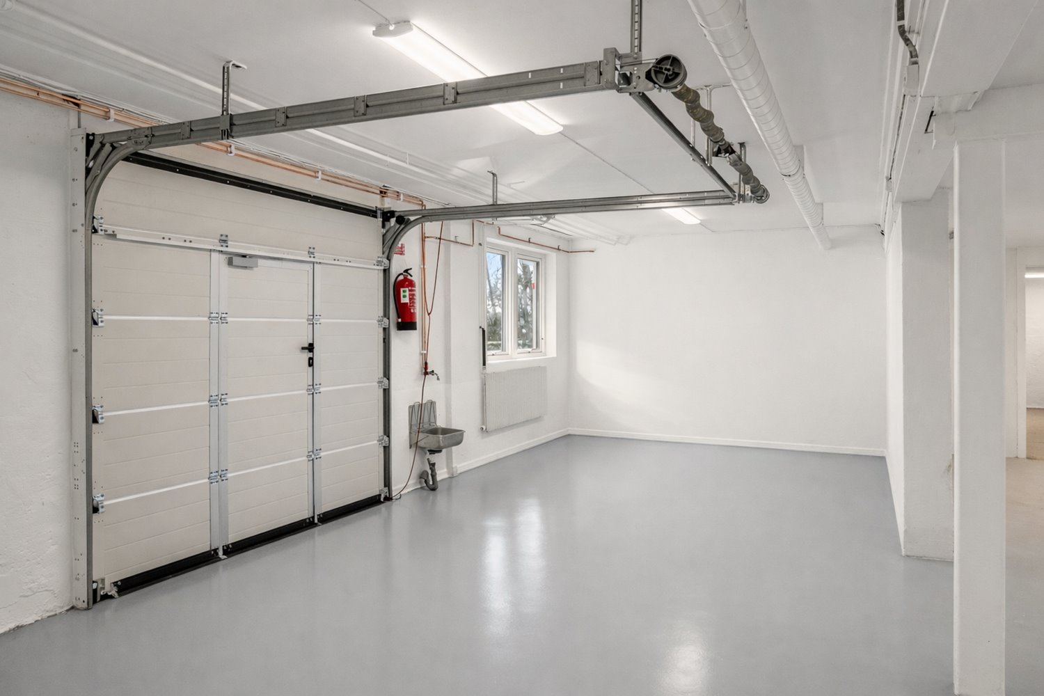 Ljus lagerdel med port och fönster som ger fint dagsljusinsläpp. Nytt golv och nymålade ytskikt skapar en modern och välskött känsla.
