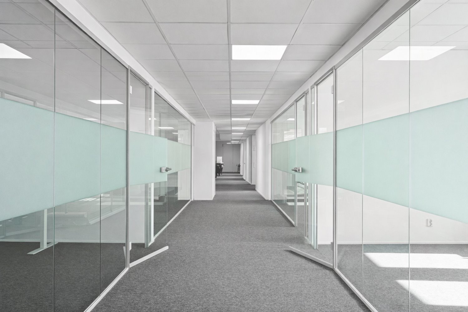 Lång korridor med glasade rum som skapar rymd och transparens