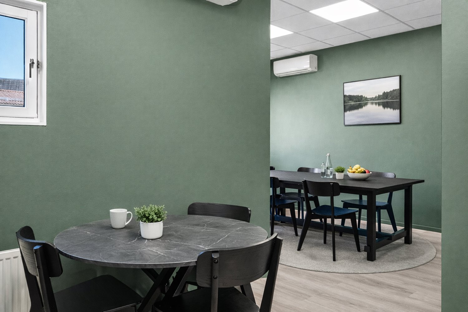 Trivsam matplats i anslutning till köket där teamet kan samlas för lunch eller kaffepauser. Den gröna färgsättningen skapar en varm och avkopplande miljö.