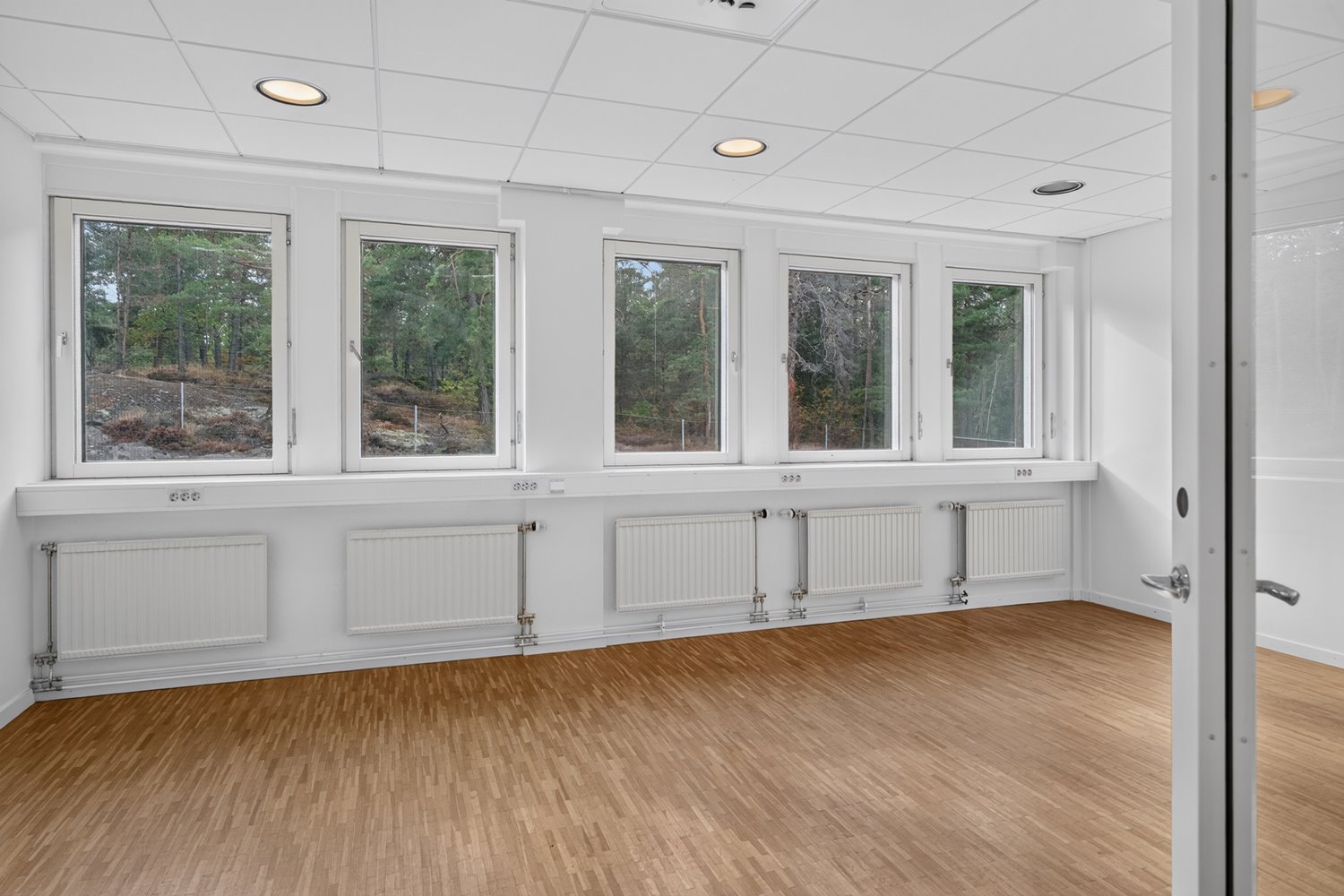 Luftigt kontorsrum med parkett och generöst ljusinsläpp
